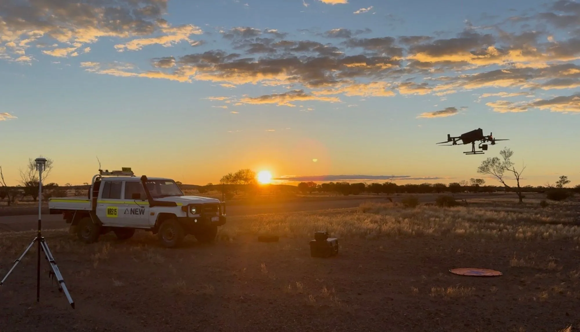 Survey crew, GNSS base and drone at sunset